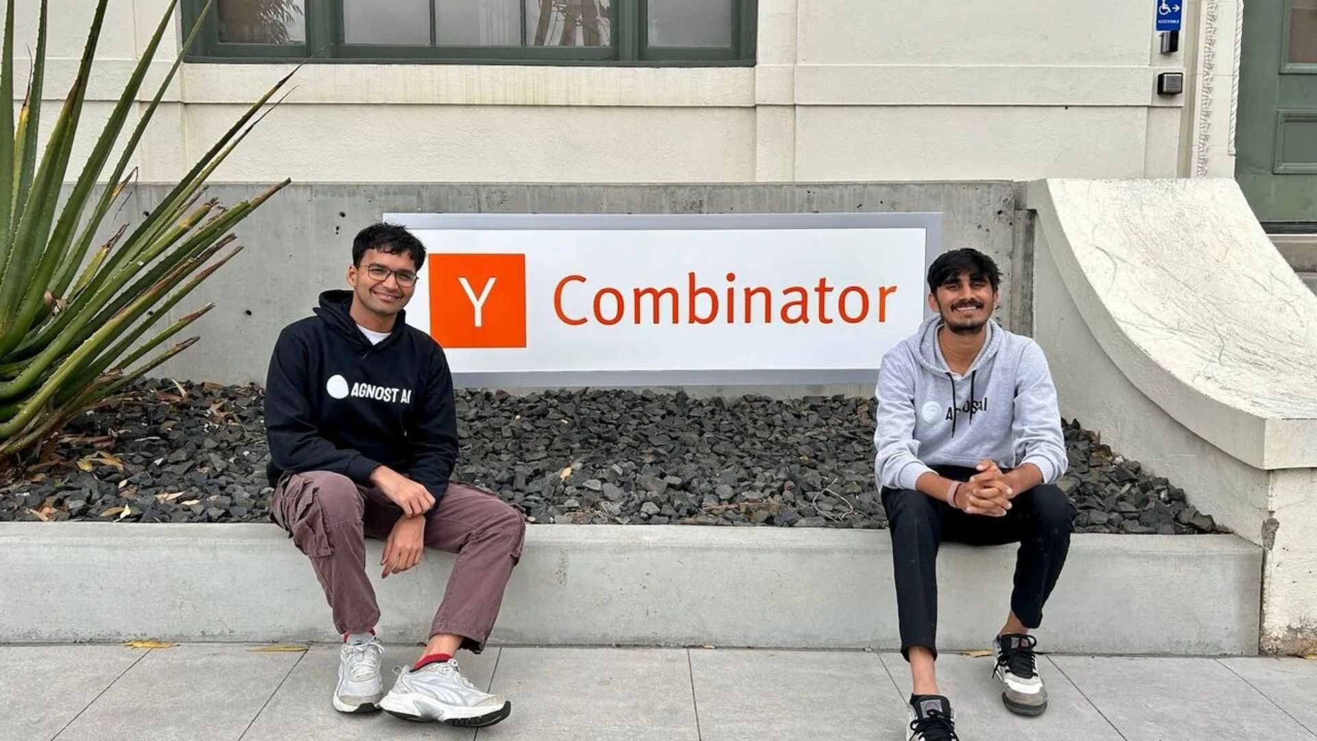Agnost AI founders Shubham Palriwala and Parth Ajmera sitting outside in front of the Y Combinator sign